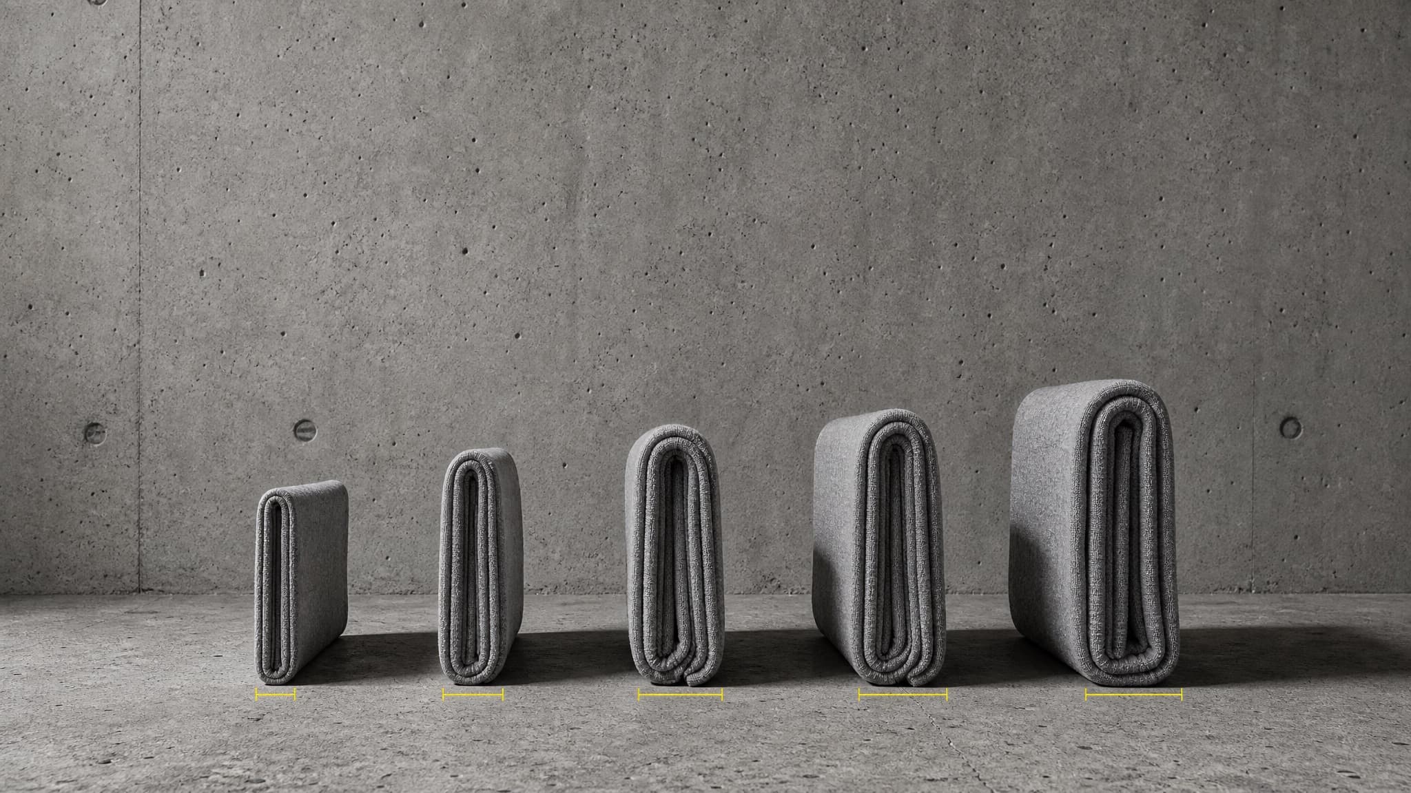 Five folds of sweatshirt cloth stood on edge in a row against concrete, each thicker than the one before it, with a measurement mark beside each